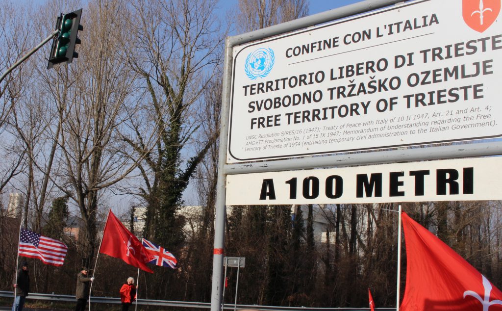 Un presidio di Trieste Libera sul confine del Territorio Libero con l'Italia. I manifestanti espongono le bandiere del Territorio Libero, del Regno Unito e degli Stati Uniti.