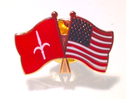 Spilla con le bandiere di Trieste e degli Stati Uniti incrociate in segno di amicizia.